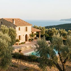 Maison provençale sur une colline du Var, entourée d’oliviers, avec une piscine discrète et la Méditerranée visible au loin dans la lumière de fin d’après-midi.